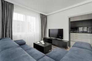 a living room with a blue couch and a tv at Luksusowy Apartament z 3 Sypialniami, Klimatyzacją, Parkingiem i Biurkiem we Wrocławiu by Renters Prestige in Wrocław
