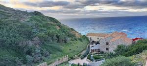 a building on a hill next to the ocean at House by the sea in Gonnesa +9 photos
