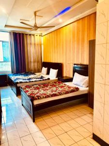 a bedroom with two beds and a ceiling at Swiss Cottage Hotel in Islamabad