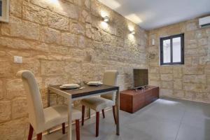 a dining table and chairs in a room with a stone wall at Cosy 1BR home in the heart of vibrant Valletta by 360 Estates in Valletta