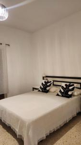 een slaapkamer met een wit bed met kussens erop bij Click & Guest - Tropical Escape in Playa de Arinaga in Agüimes