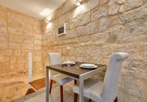 a dining room with a wooden table and white chairs at Cosy 1BR home in the heart of vibrant Valletta by 360 Estates in Valletta