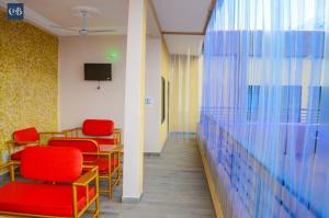 una sala de espera con sillas rojas y una pared en COMPLEXE HOTELIER LA BONTE ( CHB ), en Abomey-Calavi