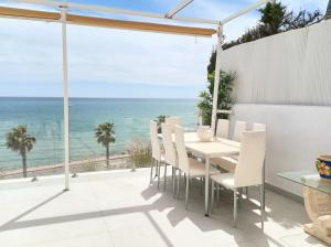 ein Esszimmer mit einem Tisch, Stühlen und Meerblick in der Unterkunft Townhouse beachfront Benalmadena-Costa in Benalmádena