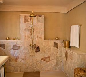 a bathroom with a shower with a stone wall at SUJÁN Sher Bagh in Sawāi Mādhopur