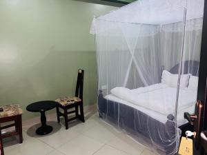 a bedroom with a canopy bed with a table and a stool at Suzie hotel old Kampala in Kampala