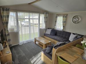 a living room with a couch and a table at Luxury Caravan 3 Bedroom 8 Berth With Hot-tub in Lincoln