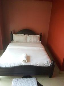 een slaapkamer met een bed met witte lakens en kussens bij Suzie hotel old Kampala in Kampala