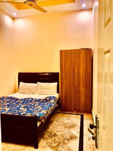 a bedroom with a bed and a wooden cabinet at Swiss Cottage Hotel in Islamabad