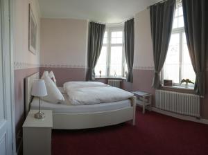 a bedroom with a white bed and two windows at Appartements Neef in Merseburg