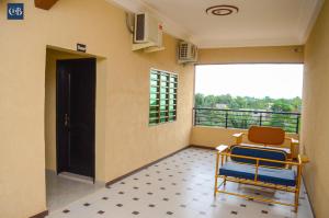 Habitación con balcón con 2 sillas y puerta. en COMPLEXE HOTELIER LA BONTE ( CHB ), en Abomey-Calavi