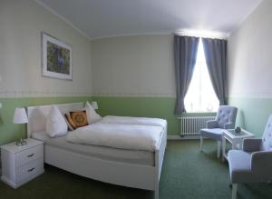 1 dormitorio con 1 cama blanca y 1 silla en Appartements Neef, en Merseburgo