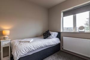 een kleine slaapkamer met een bed en een raam bij SPACIOUS HOME WITH GARDEN-SLEEPS 5 Contractors, families, and group stays welcome in Beeston