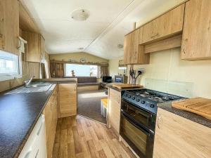 uma cozinha com armários de madeira e um forno com placa de fogão em Dog Friendly Caravan With Large Decking Near Heacham Beach, Ref 21052h em Heacham