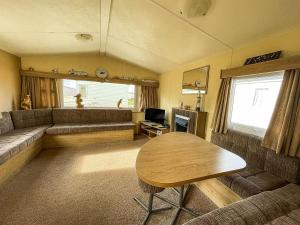 uma sala de estar com um sofá e uma mesa em Dog Friendly Caravan With Large Decking Near Heacham Beach, Ref 21052h em Heacham