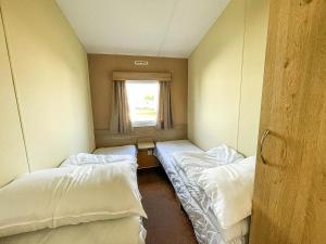 um quarto com três camas e uma janela em Dog Friendly Caravan With Large Decking Near Heacham Beach, Ref 21052h em Heacham