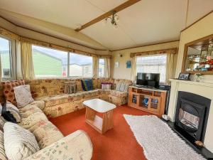 sala de estar con sofá y chimenea en 8 Berth Caravan For Hire At Heacham Holiday Park In Norfolk Ref 21024f, en Heacham
