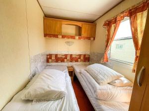 a small room with two beds and a window at 8 Berth Caravan For Hire At Heacham Holiday Park In Norfolk Ref 21024f in Heacham