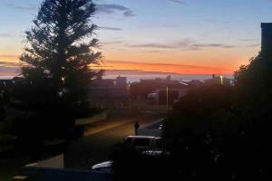 a person standing in a parking lot next to a tree at Sunset View Self- Catering Yzerfontein in Yzerfontein