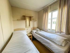 2 camas en una habitación pequeña con ventana en 8 Berth Caravan For Hire By The Beach In Heacham, Norfolk Ref 21038c, en Heacham