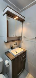 a bathroom with a sink and a toilet and a mirror at Apto BENTO! LAREIRA e CHURRASQUEIRA! in Bento Gonçalves +27 photos