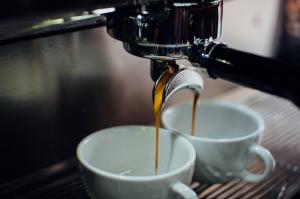 a coffee machine pouring coffee into two white cups at Hotel Mare Blu -- boutique in Pineto