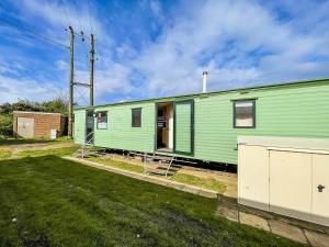 una casa verde sentada en la parte superior de un patio en 8 Berth Caravan With Free Wifi At Heacham Holiday Park In Norfolk Ref 21008e, en Heacham