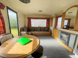 sala de estar con mesa y sofá en 8 Berth Caravan With Free Wifi At Heacham Holiday Park In Norfolk Ref 21008e, en Heacham