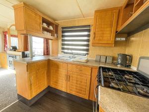 cocina con armarios de madera y horno con fogones en 8 Berth Caravan With Free Wifi At Heacham Holiday Park In Norfolk Ref 21008e, en Heacham