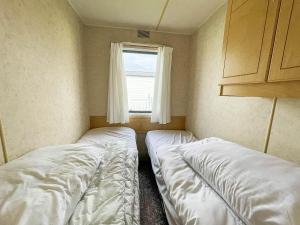2 camas en una habitación pequeña con ventana en 8 Berth Caravan With Free Wifi At Heacham Holiday Park In Norfolk Ref 21008e, en Heacham
