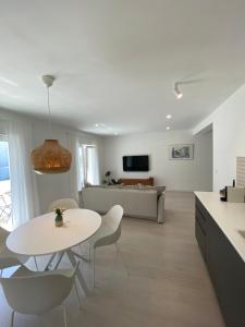 eine Küche und ein Wohnzimmer mit einem weißen Tisch und Stühlen in der Unterkunft FeelAtHome Hvar Apartments in Hvar