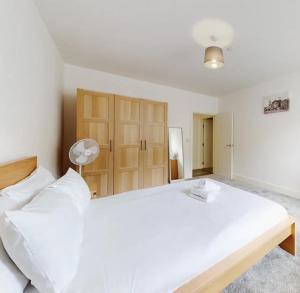 een grote slaapkamer met een groot wit bed en houten kasten bij Spacious two bedroom apartment with Valley views in Abertillery