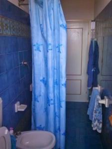 y baño con cortina de ducha azul y aseo. en Apartment for holiday rent in Marina di Cecina, en Cecina