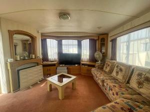 a living room with a couch and a tv at 6 Berth Caravan With Decking Nearby Heacham Beach In Norfolk Ref 21047a in Heacham