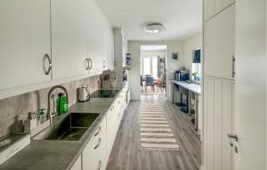 a kitchen with white cabinets and a wooden floor at Cozy Home In Stokmarknes With House A Mountain View in Stokmarknes