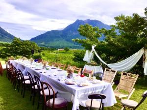 a long white table with chairs and mountains in the background at Yufuin Tsukawara Kogen Sanctuary - Vacation STAY 91378v in Yufuin