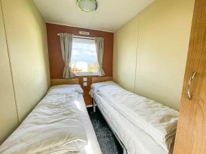 2 camas en una habitación pequeña con ventana en Lovely 6 Berth Caravan At Heacham Beach Holiday Park, Norfolk Ref 21020g, en Heacham