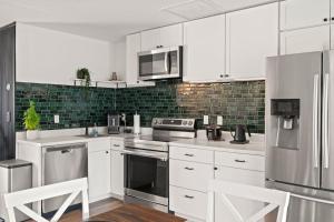 a kitchen with white cabinets and stainless steel appliances at Brand New 2Bed in Bonita's Heart with Superb Patio and Garden in Bonita Springs