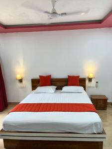 um quarto com uma cama grande e almofadas vermelhas em Usha Resort em Pālghar