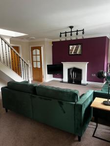 a living room with a green couch and a fireplace at Ida House in Ormesby