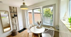 a table and chairs in a room with windows at Lust auf Meer - Ferienappartement in Cuxhaven +7 photos