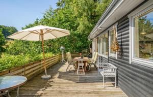 eine Holzterrasse mit einem Tisch und einem Sonnenschirm in der Unterkunft 3 Bedroom Stunning Home In Ebeltoft in Ebeltoft