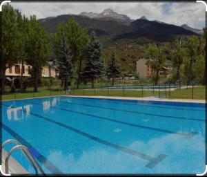 a large blue swimming pool with mountains in the background at El nido de Villanua in Villanúa