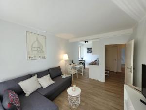 a living room with a gray couch and a kitchen at Mit Blick in den Emsseepark in Warendorf