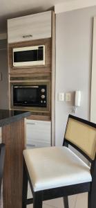 a kitchen with a microwave and a table and a chair at Apê BENTO com churrasqueira! in Bento Gonçalves