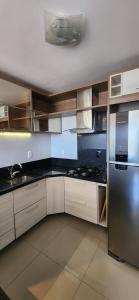 a kitchen with white cabinets and a stainless steel refrigerator at Apê BENTO com churrasqueira! in Bento Gonçalves