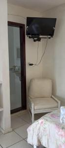 um quarto com uma cadeira e uma televisão de ecrã plano em Axé Brasil em Búzios