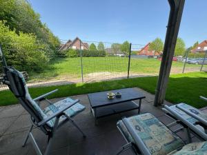 a patio with three chairs and a table and a field at Ferienwohnung 24A Unten Links 3 Zimmer in Lathen