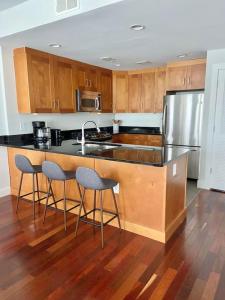 una cocina con armarios de madera y una isla de cocina con 2 taburetes en 440-Luxury Apt Near Light Rail, en Hoboken