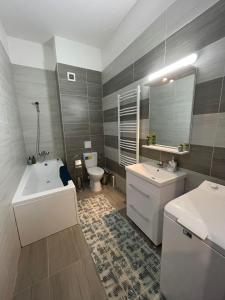 uma casa de banho com 2 lavatórios, uma banheira e um WC. em Divine Apartments River Towers em Iaşi